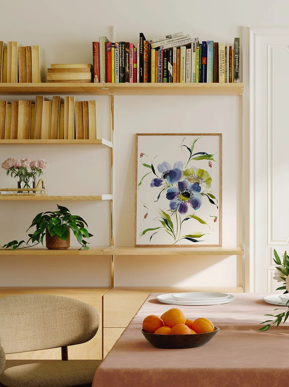 Blue anemone print displayed on a bookshelf behind a dining table.