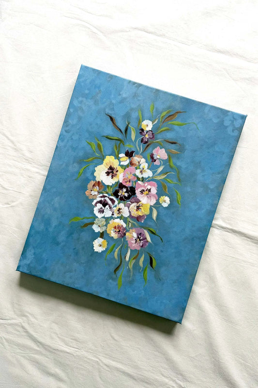 A canvas painting featuring a colorful floral bouquet on a textured sky blue background.