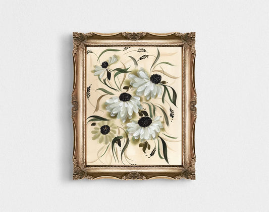 White daisy print in an ornate gold frame on a pale wall.