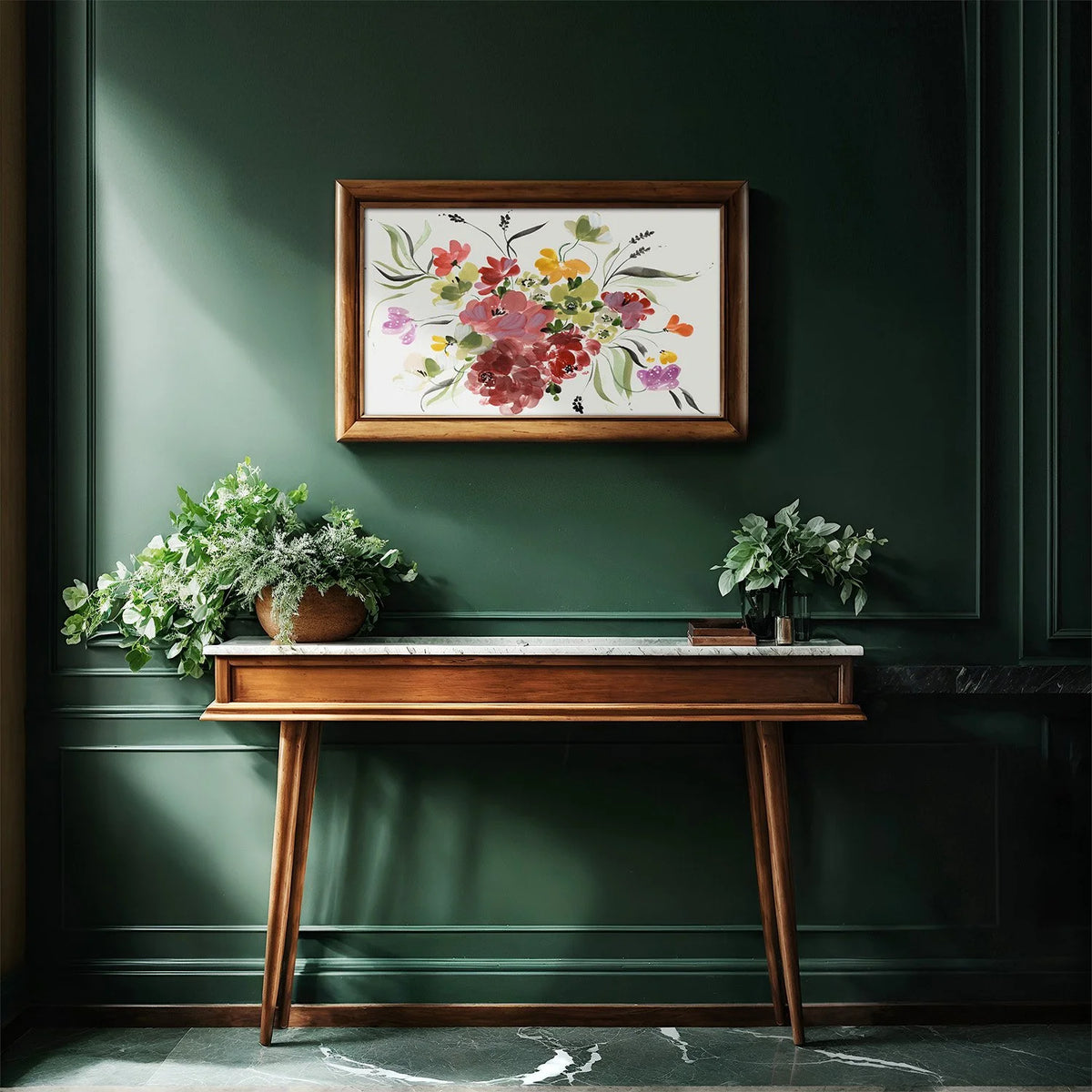 Horizontal colorful floral print in a gold frame above a wooden console on a dark green wall.