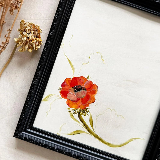A framed floral original featuring a painted red-orange anemone with green stems on an off-white background, shown in a black ornate frame