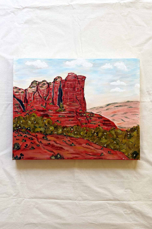 A landscape painting of red rock desert cliffs of Sedona Coffee Pot Rock under a blue sky. Commission by Ramya Rajiv