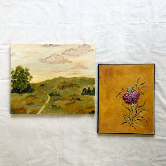 Two original paintings by Ramya Rajiv displayed side-by-side. The left painting depicts a landscape with rolling green hills, a winding path, trees, and a cloudy sky.
