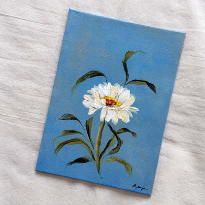 A small canvas original of a white daisy with green leaves on a blue background