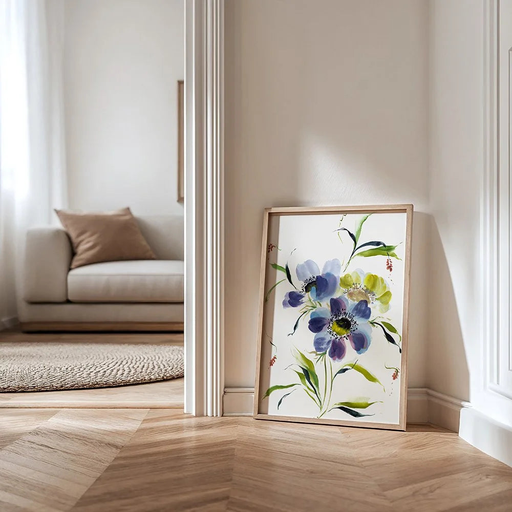 Blue anemone print in a light wood frame leaning against a hallway wall.