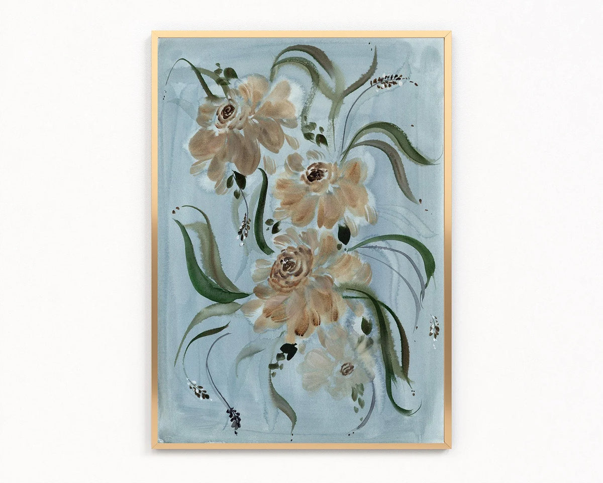 Gold-framed print of beige and brown ranunculus with sweeping green leaves on pale blue.