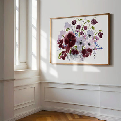 Horizontal burgundy floral vase print in a gold frame beside a sunlit window.