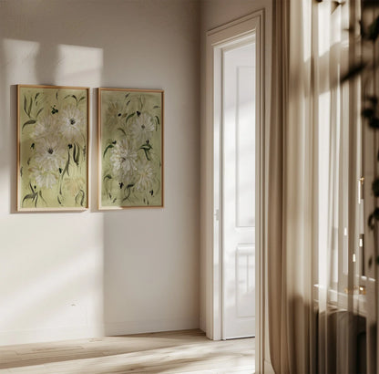 Two white dahlia prints in light wood frames on a sunlit hallway wall.
