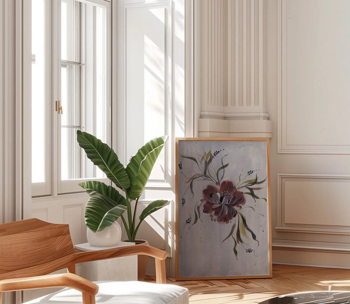 Large burgundy anemone print leaning beside a potted plant and chair in a sunlit room.