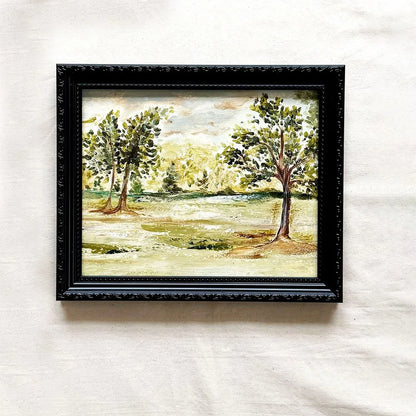 A framed original landscape painting featuring green trees and a grassy field, housed in a black ornate frame by Ramya Rajiv