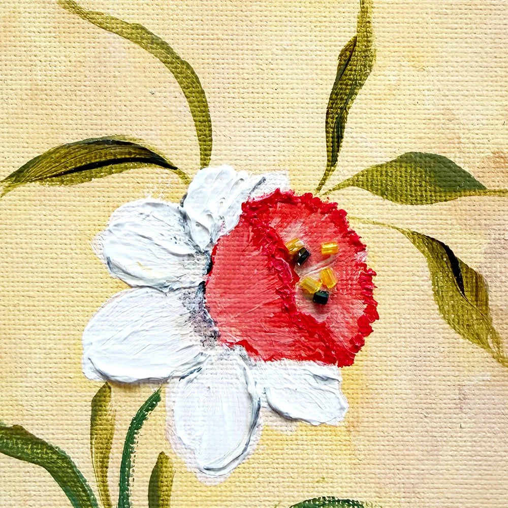 A close-up of a painted flower on textured canvas, featuring a white bloom with a vivid red center and green leaves 
