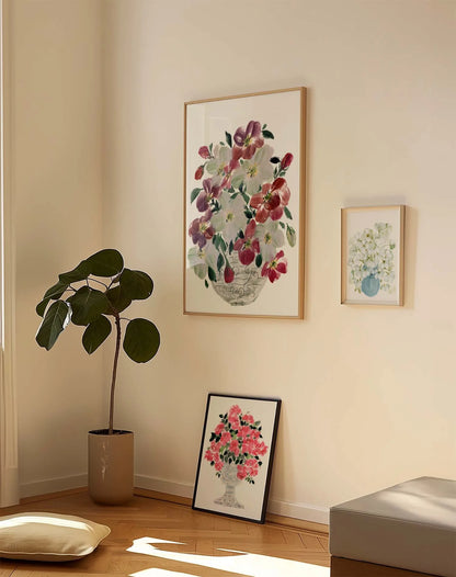 Large hellebore vase print displayed with smaller rose and white-flower prints beside a potted plant.