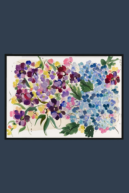Black-framed print of blue hydrangeas and purple and pink flowers displayed on a deep blue wall.