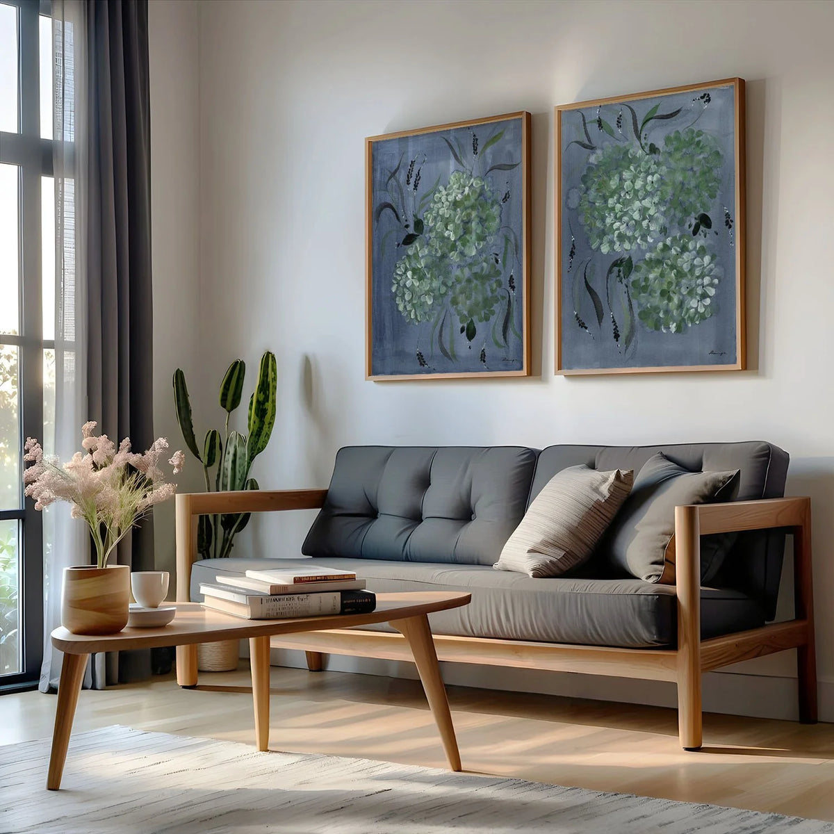 Two blue-background hydrangea prints in gold frames above a gray sofa.