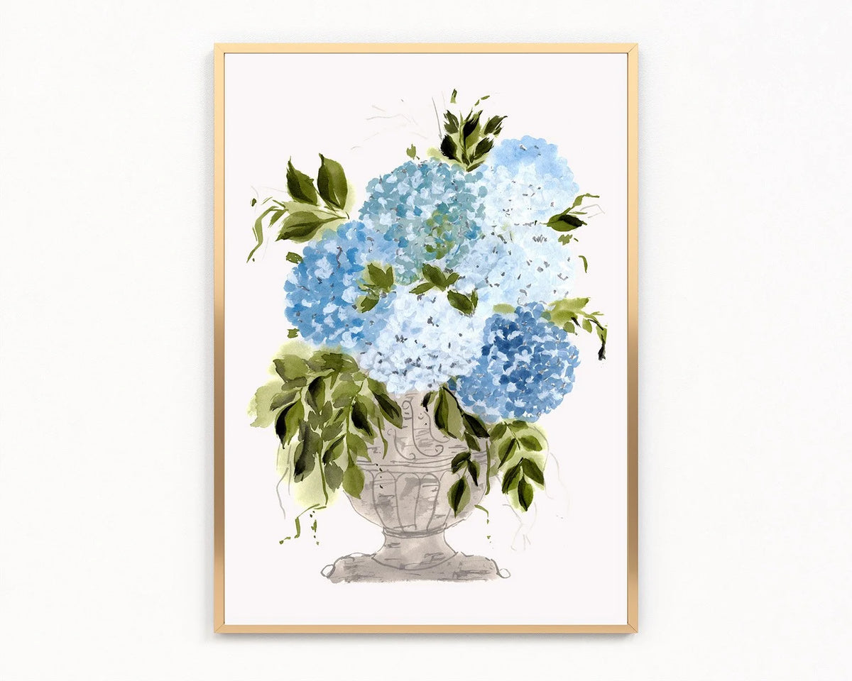 Gold-framed print of blue and white hydrangeas with green leaves in a decorative pedestal vase.