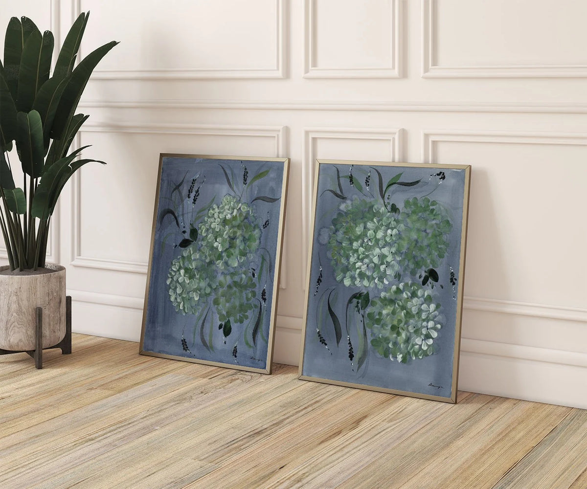 Two hydrangea prints leaning against a white paneled wall beside a potted plant.