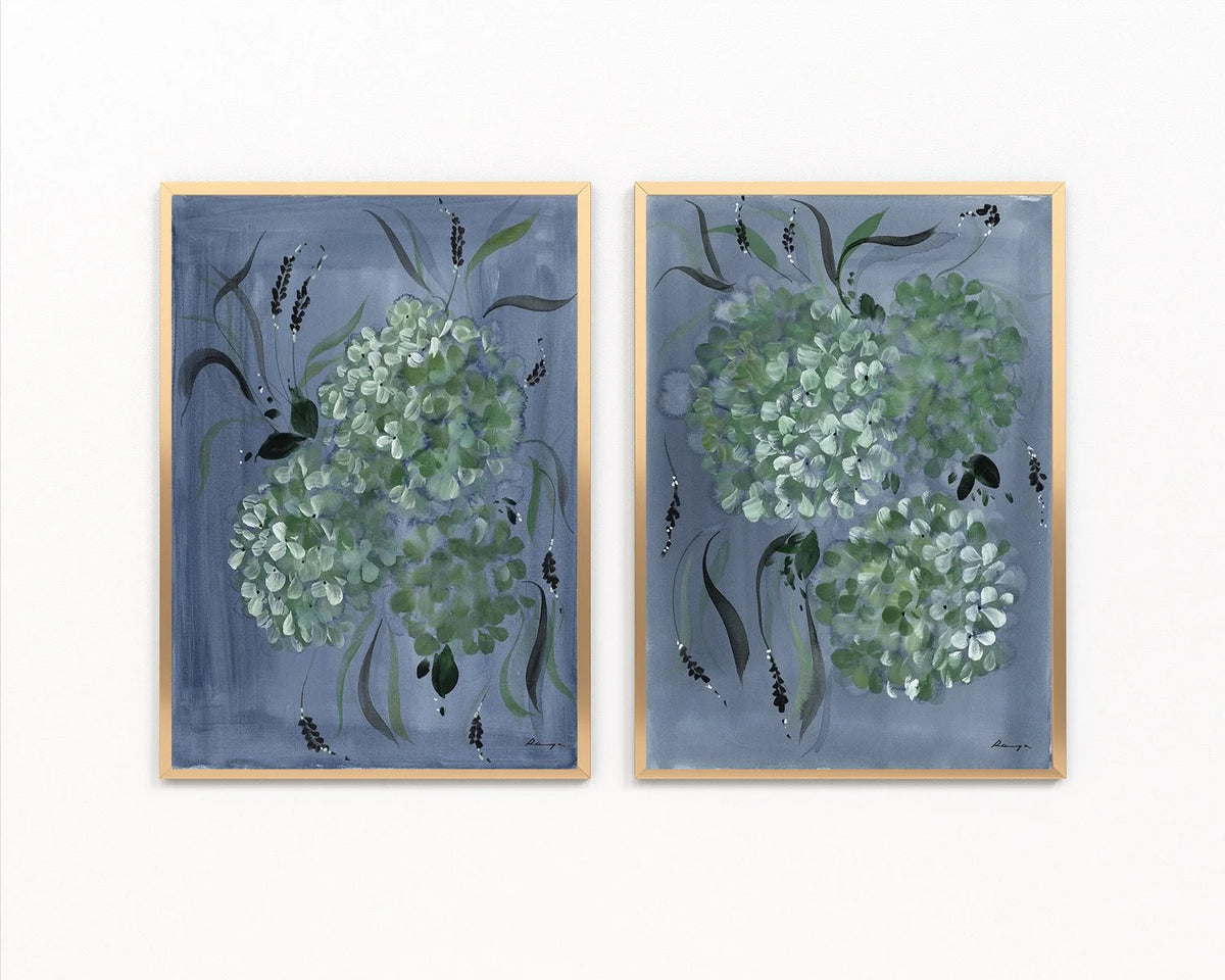 Pair of gold-framed prints with pale green hydrangeas and dark leaves on blue backgrounds.