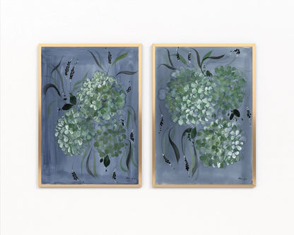 Pair of gold-framed prints with pale green hydrangeas and dark leaves on blue backgrounds.