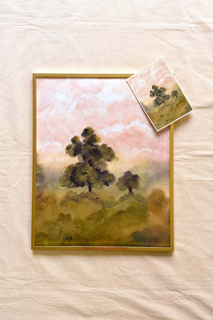 A framed landscape painting featuring dark green trees under a soft pink and beige sky alongside the original 5x7 landscape painting