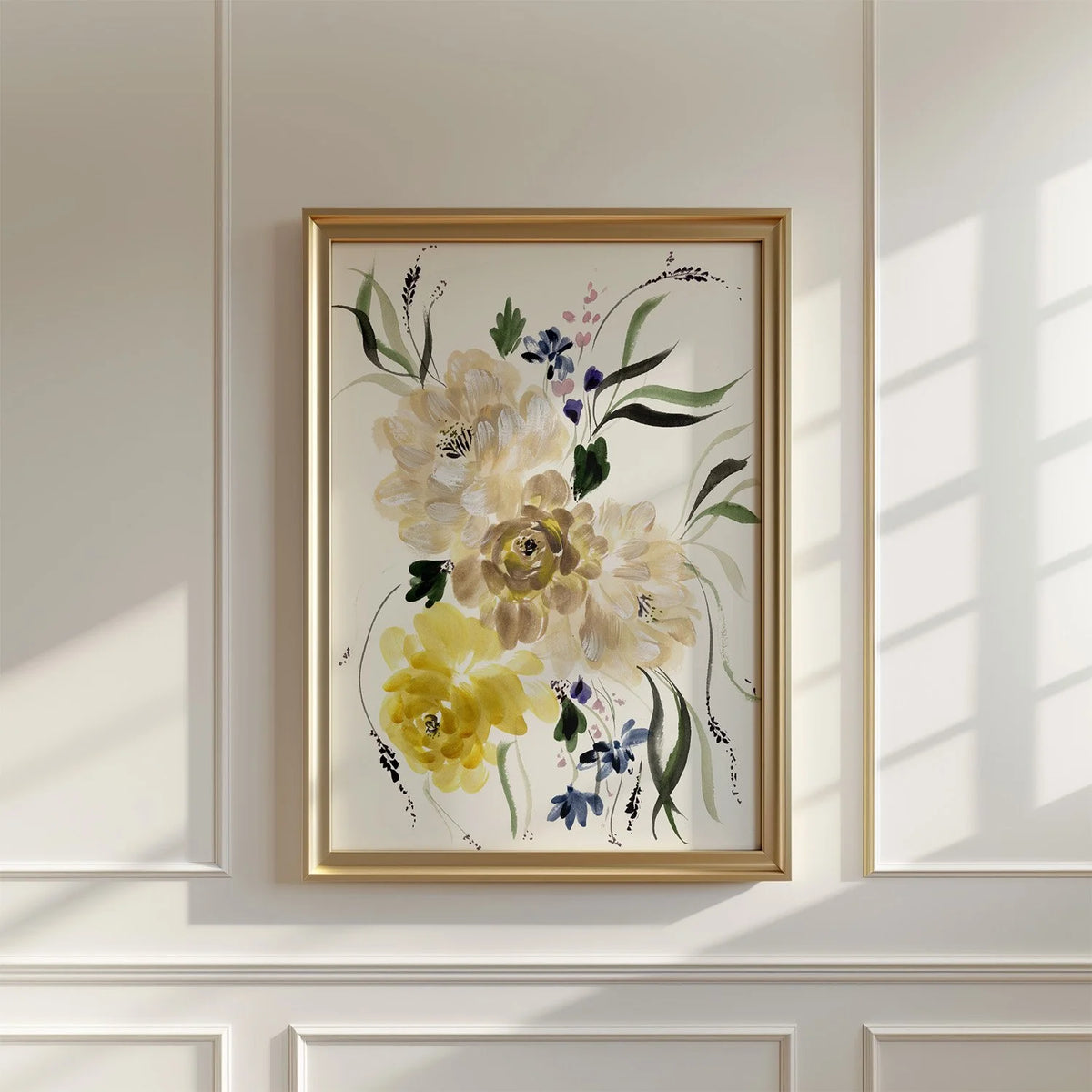 Cream and yellow floral print in a brass-colored frame on a sunlit paneled wall.