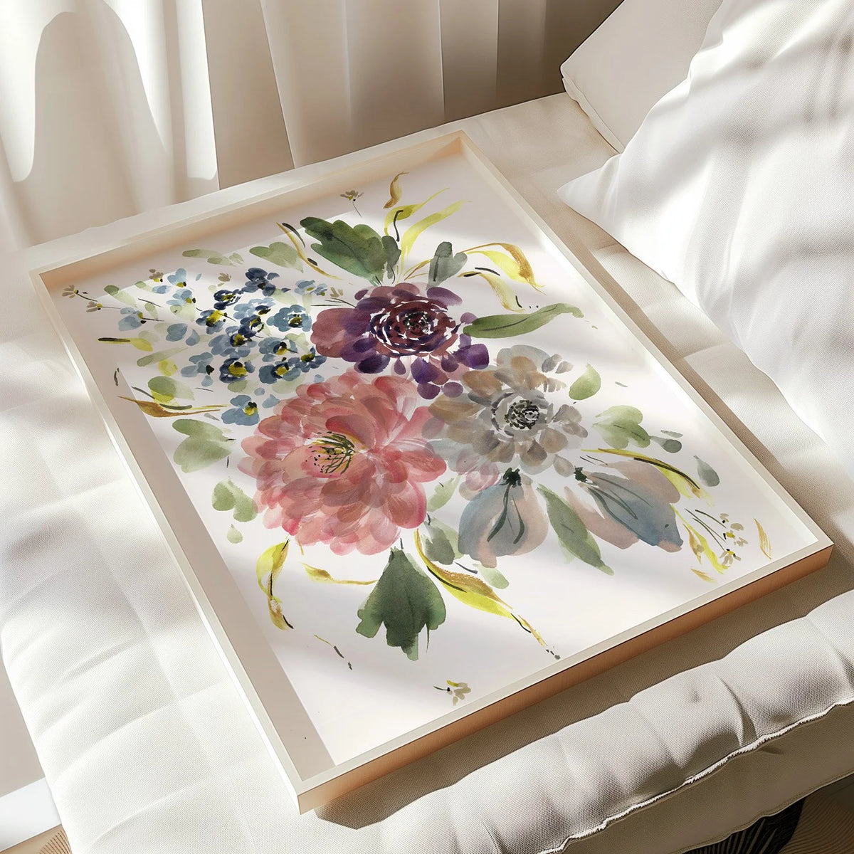 Framed mixed floral print resting on a white cushioned chair in sunlight.