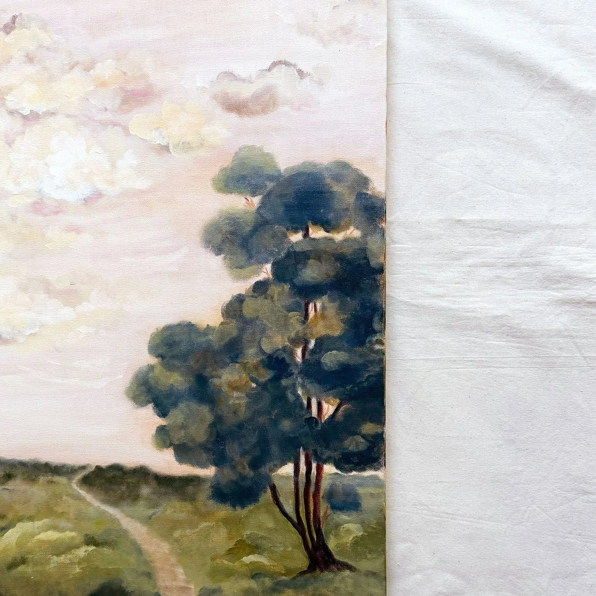 A close-up of a landscape original painting showing a large dark green tree beside a pale pink sky and winding path