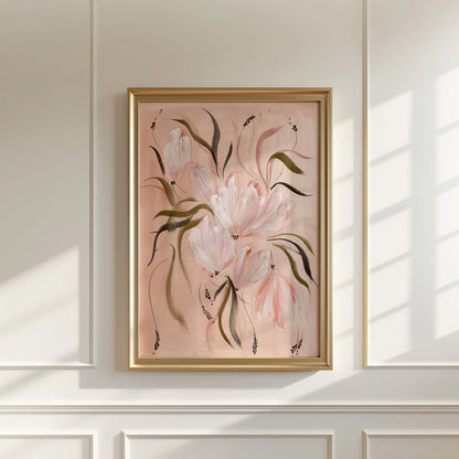 A framed floral wall art print hangs on a white paneled wall. The artwork features soft pink tulips with dark green leaves on a blush pink background, enclosed in a thin gold frame.