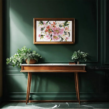 A framed floral art print hangs on a dark green paneled wall above a wooden console table with potted plants in a styled interior setting.