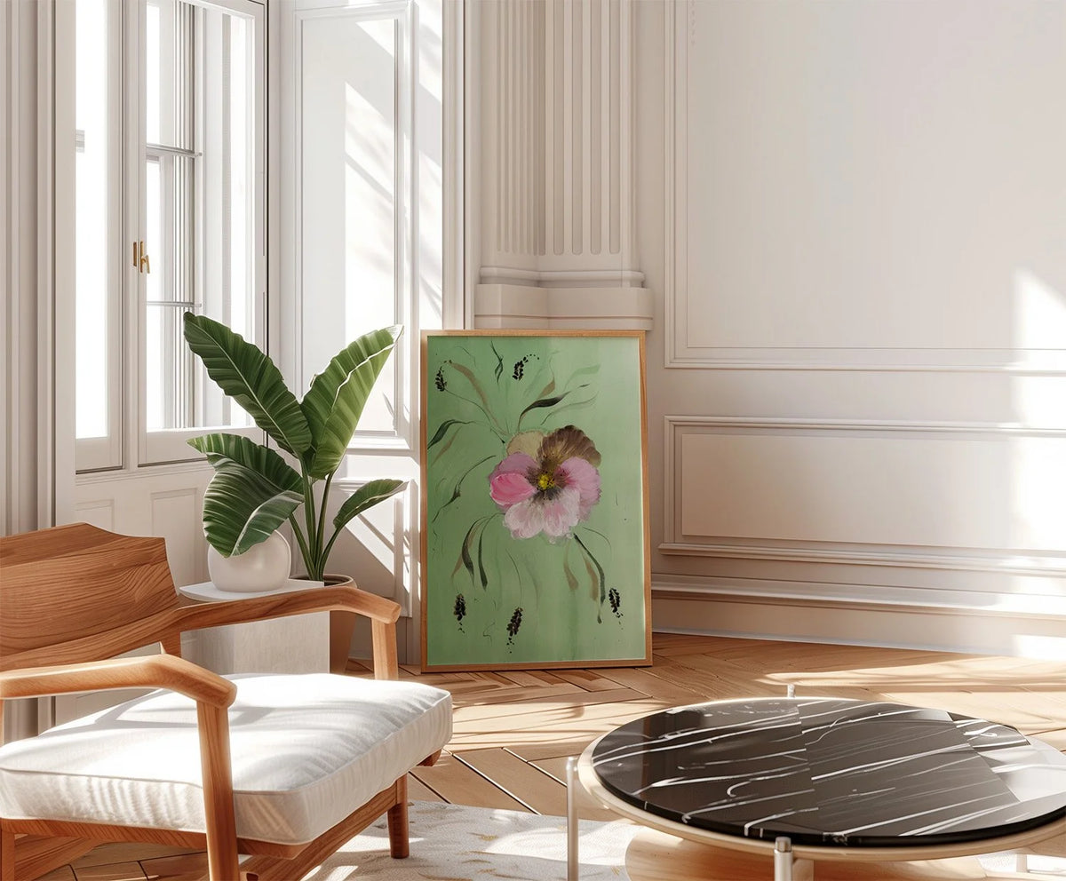 Pink pansy print on green leaning beside a potted plant and chair in a sunlit room.