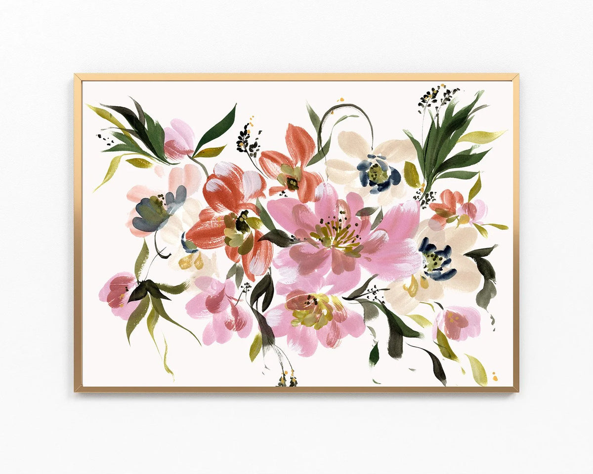 A framed watercolor floral art print featuring pink, coral, green, and blue blossoms on a white background, enclosed in a light wood frame against a white wall.