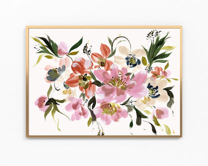 A framed watercolor floral art print featuring pink, coral, green, and blue blossoms on a white background, enclosed in a light wood frame against a white wall.