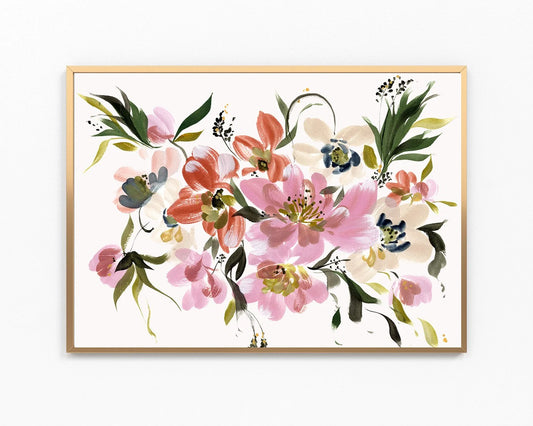 A framed watercolor floral art print featuring pink, coral, green, and blue blossoms on a white background, enclosed in a light wood frame against a white wall.