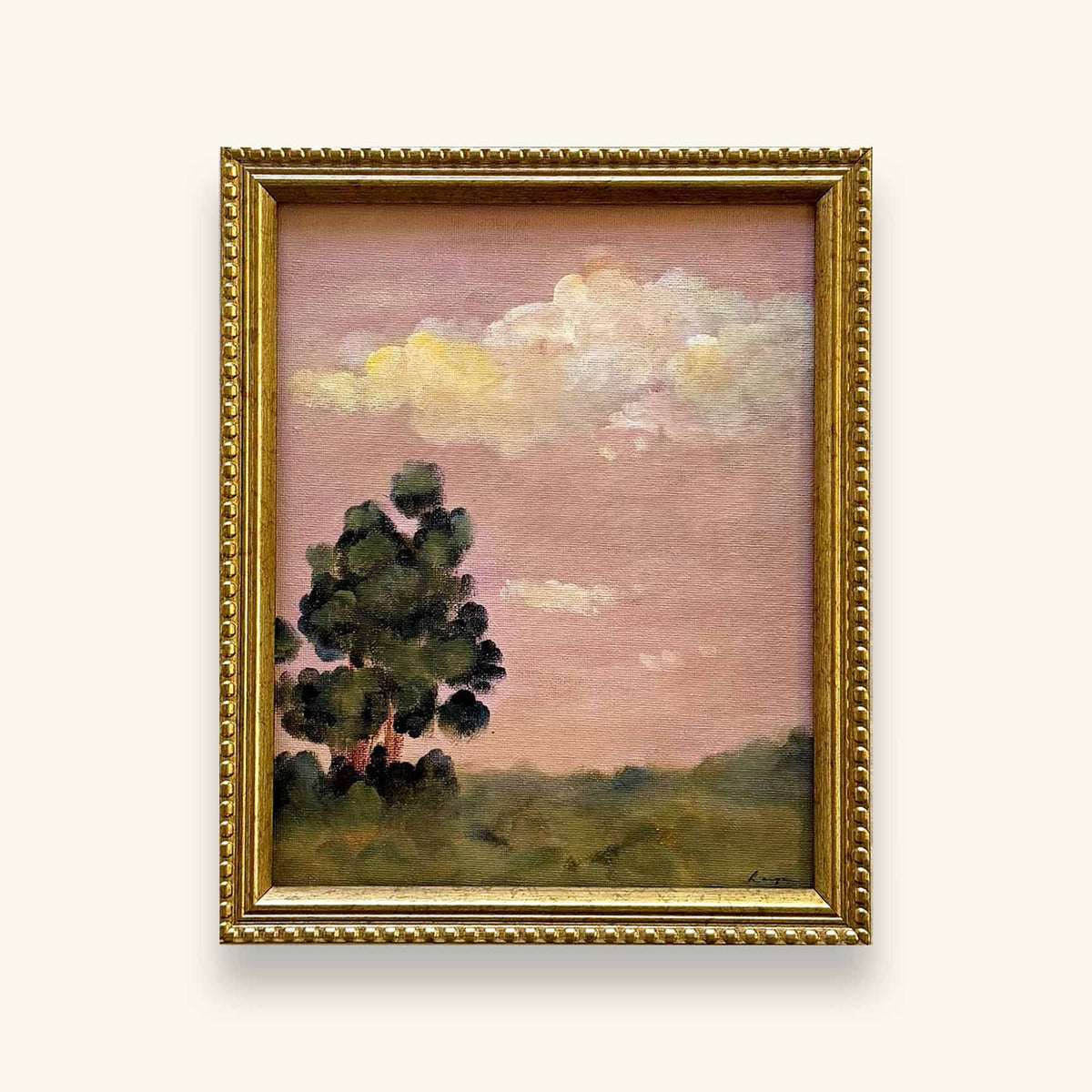 A beaded gold framed landscape original painting featuring a dark green tree under a dusty pink sky with soft yellow and white clouds, housed in an ornate gold frame 