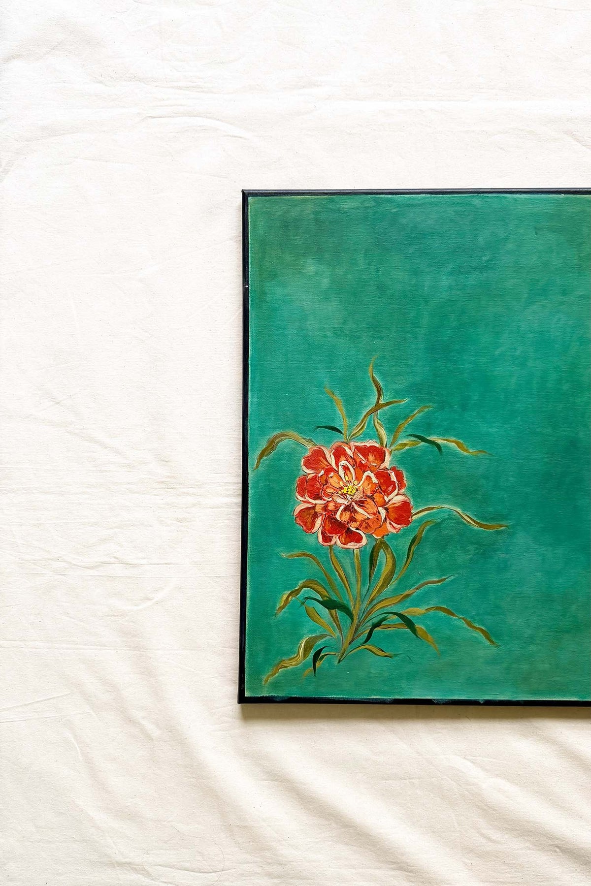 A framed painting featuring a vibrant red and orange flower with green leaves on a textured teal background Original artwork by Ramya Rajiv