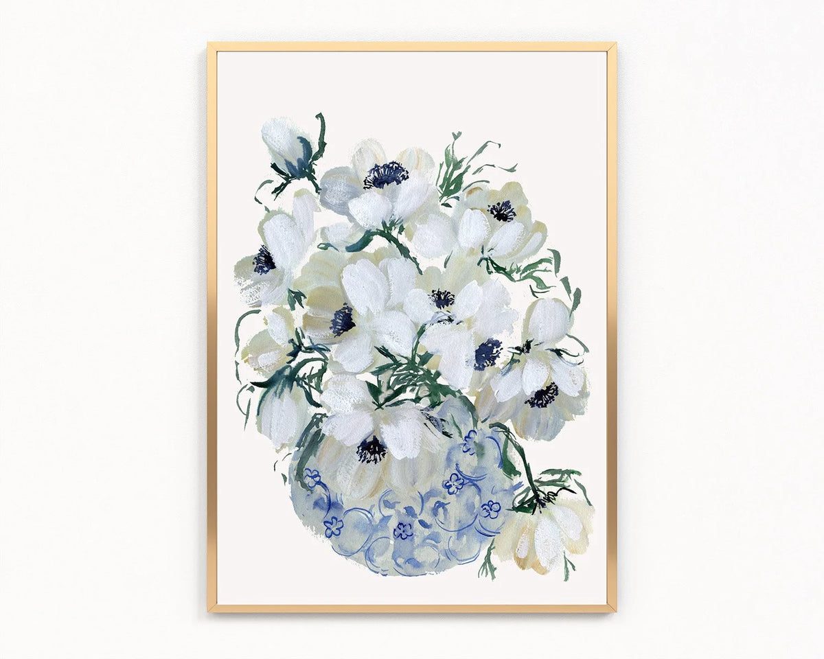 Gold-framed print of white anemones with dark blue centers in a blue-patterned vase.