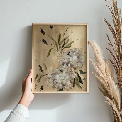 Hand holding a light wood frame containing a white dahlia print beside dried grasses.