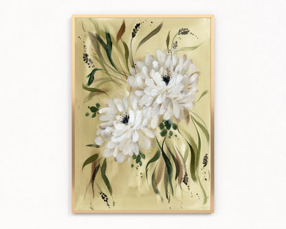 Gold-framed print of two white dahlias with flowing green leaves on a warm yellow-green background.