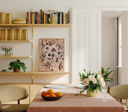 White anemone print on peach displayed on a bookshelf behind a dining table.