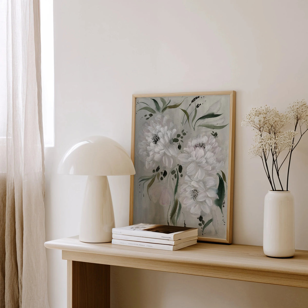 White peony print on gray resting on a wooden console beside a white lamp and vase.