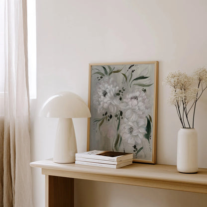 White peony print on gray resting on a wooden console beside a white lamp and vase.