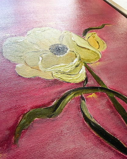 A close-up of a textured oil painting depicting a pale yellow anemone flower with a dark gray center, green stem, and a small yellow bud against a deep pinkish-red background.