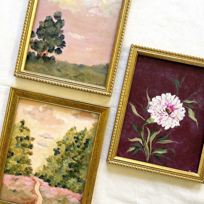 Three framed vintage watercolor paintings. One painting depicts a tree in a landscape, one shows a winding path through trees, and one features a white peony flower on a deep burgundy background with gold frames. Perfect for a gallery wall