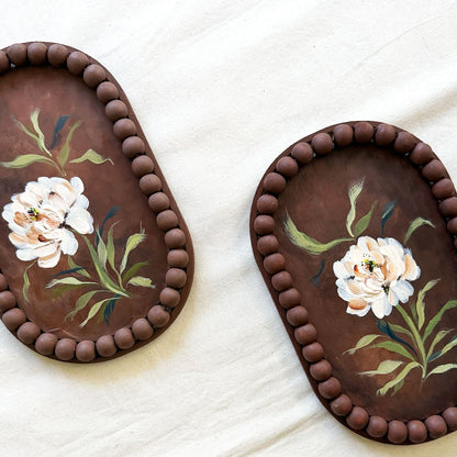 Two oval brown trays with beaded edges and hand-painted white flowers with green leaves