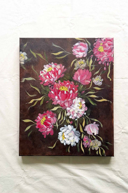 A canvas painting featuring a bouquet of pink, white, and light purple flowers with yellow centers on a dark brown background, displayed against a white fabric backdrop. Floral original painting by Ramya Rajiv