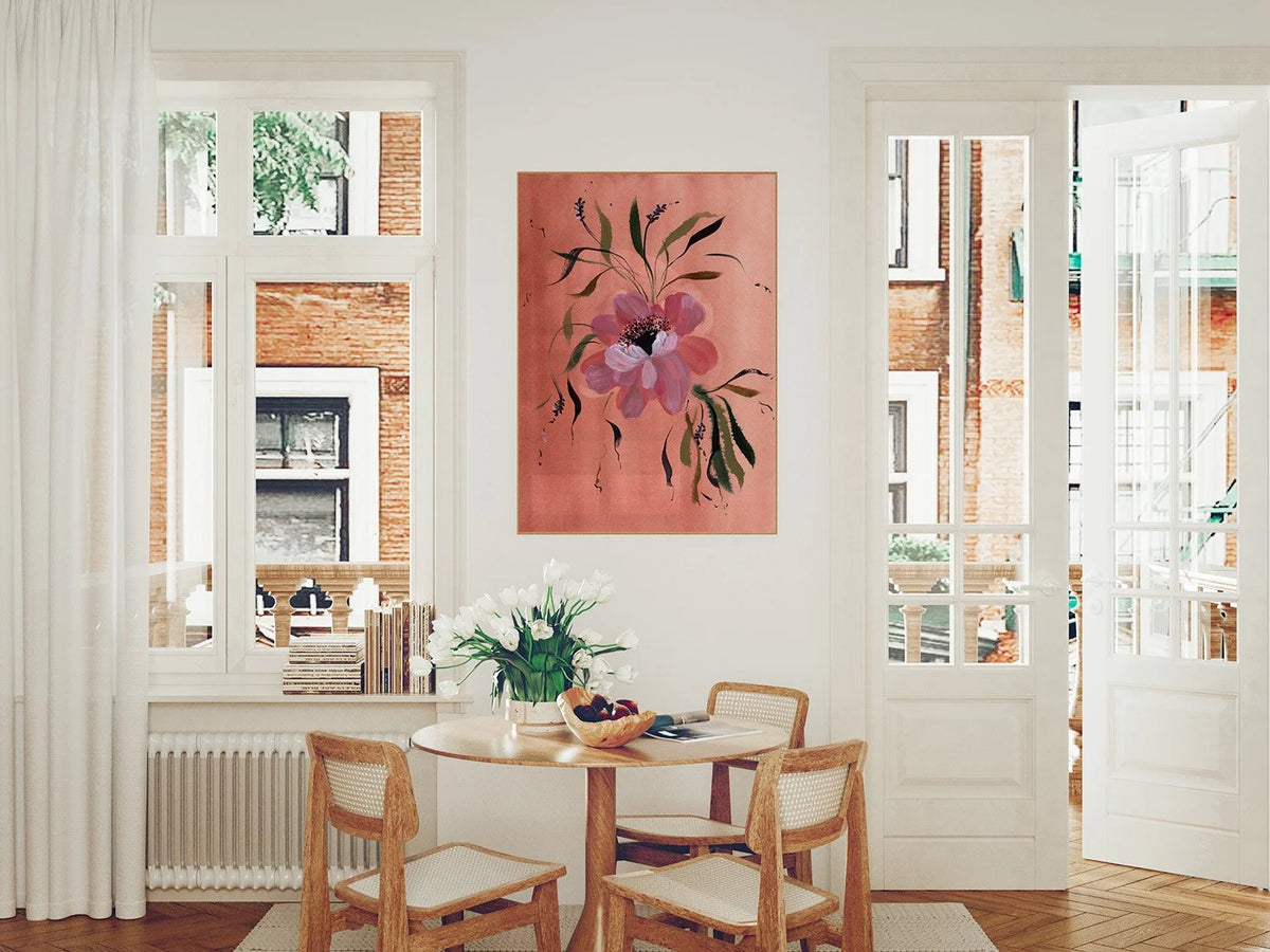Large pink anemone print on coral above a round dining table between two windows.